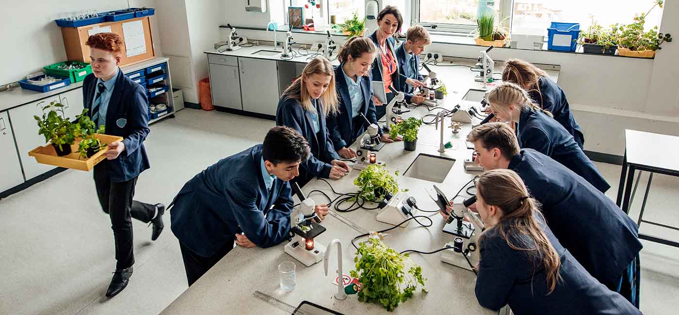 High school students in science class with teacher examining plants with microscopes!''