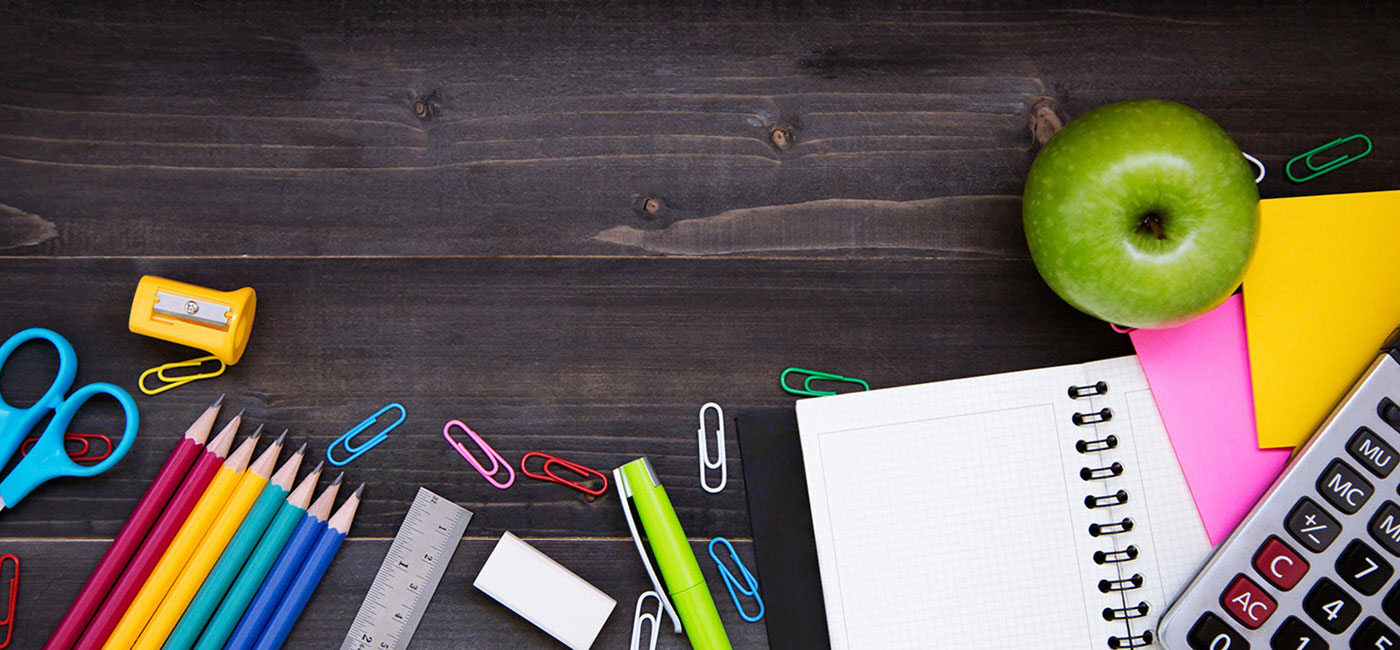 Table with apple, pens, paper, pencils, and other school supplies