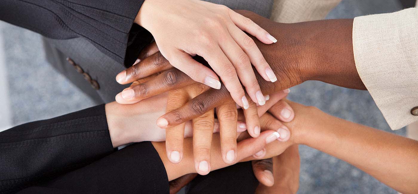 Hands of people with different racial backgrounds stacked.!''